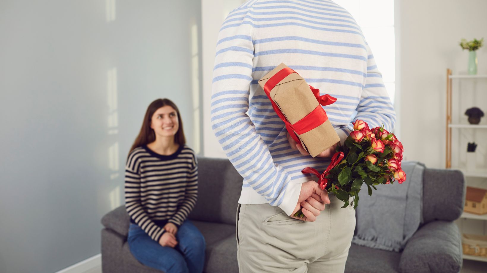 A man surprising a woman with gift and glowers